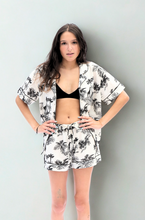 Load image into Gallery viewer, Woman wearing a cream and black pyjama set with tropical print