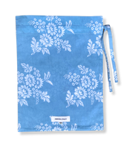 Load image into Gallery viewer, Blue fabric bag with white floral patterns and a visible brand label on a white background