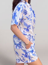 Load image into Gallery viewer, A woman modeling a short-sleeve white shirt and matching shorts set with a blue floral toile pattern, posed against a solid light gray studio background.