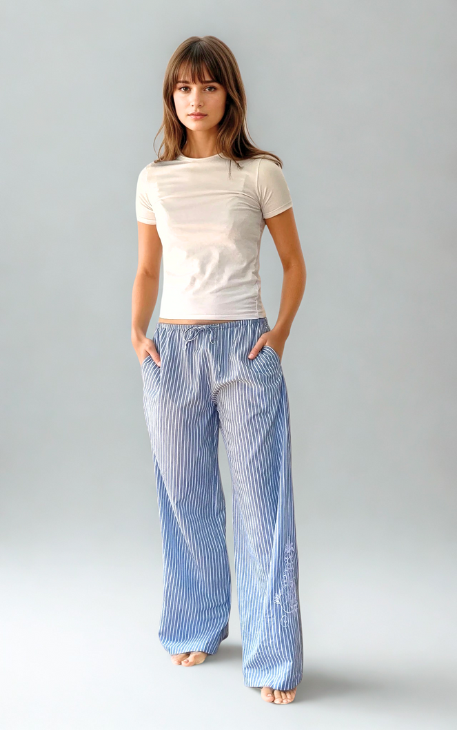 Woman wearing a white t-shirt and blue striped pants on a gray background