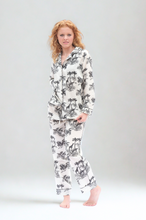 Load image into Gallery viewer, Woman wearing a white pajama set with black palm tree pattern on a plain background
