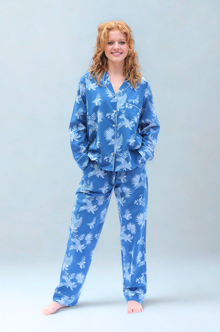 Woman wearing blue tropical print pyjamas on a light gray background