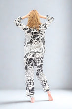Load image into Gallery viewer, Person wearing a black and white floral patterned pyjama against a plain background
