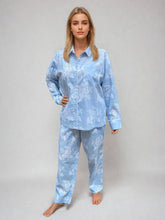 Load image into Gallery viewer, Woman wearing a light blue pajama set with floral pattern on a plain background
