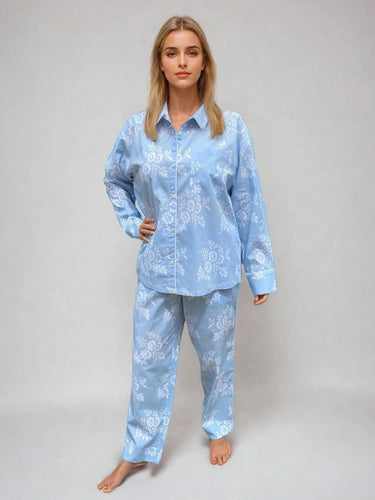 Woman wearing a light blue pajama set with floral pattern on a plain background