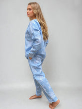Load image into Gallery viewer, Woman wearing a light blue pajama set with a floral pattern on a plain background
