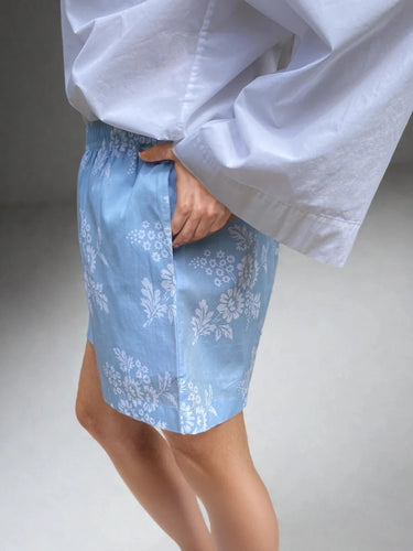 Person wearing light blue shorts with white floral patterns.