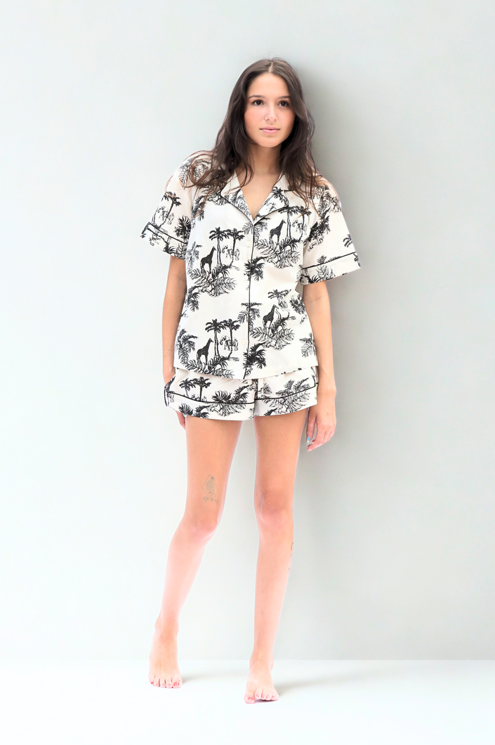 Woman wearing a tropical short pyjama set on a white background