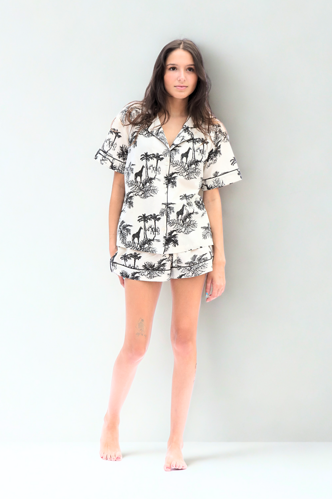 Woman wearing a tropical short pyjama set on a white background